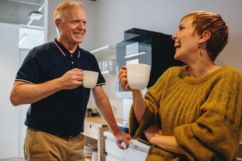 Et par kolleger prater rundt kaffemaskinen