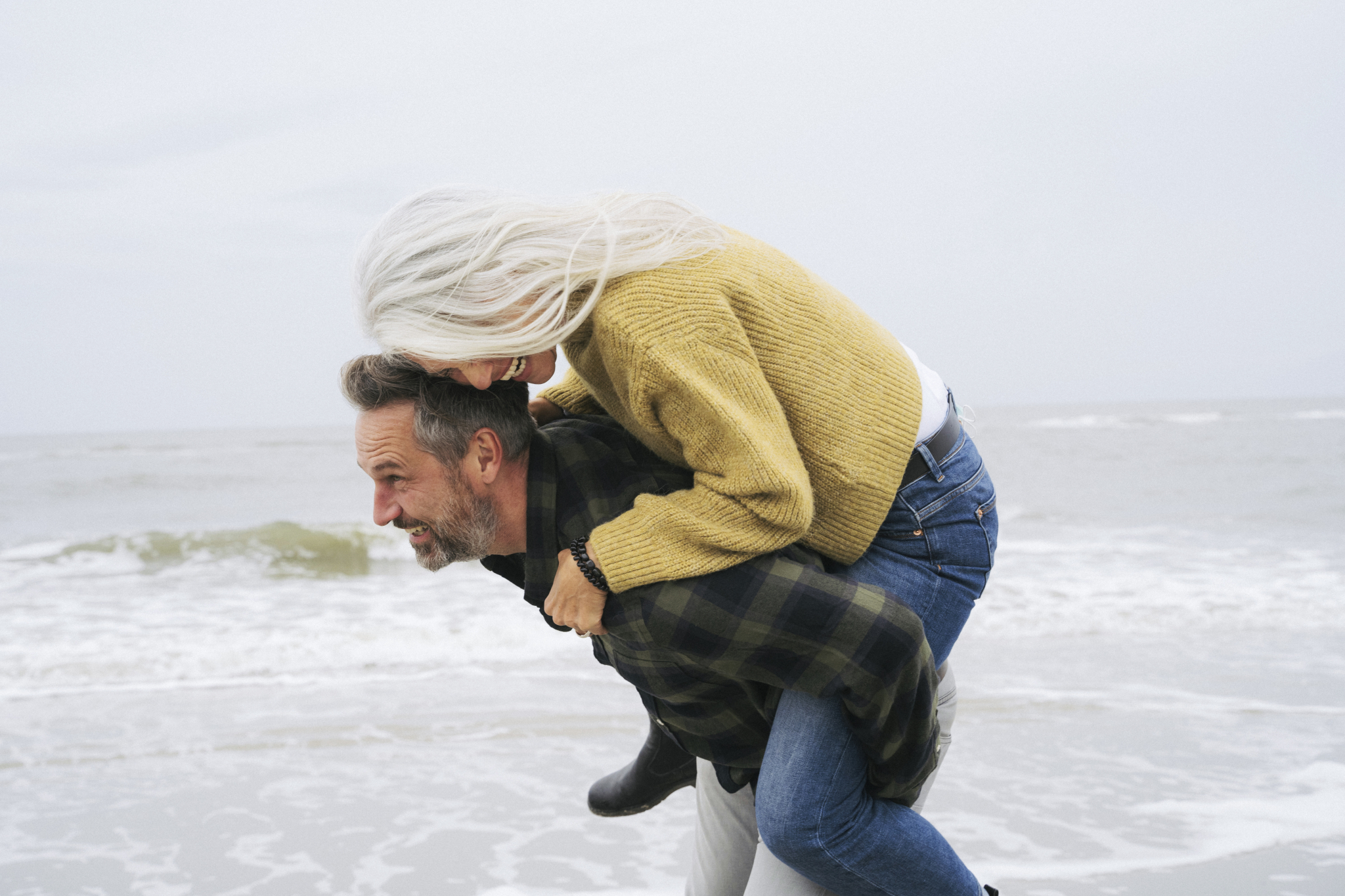 Mann bærer kvinne på ryggen på en strand